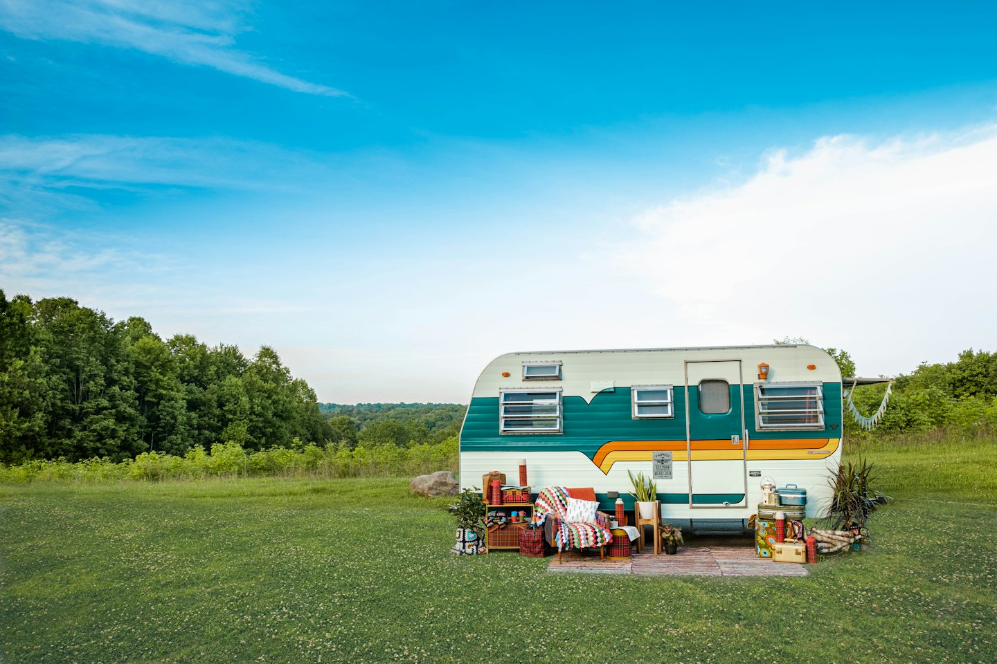 Vintage travel trailer with outdoor living area on a lawn.