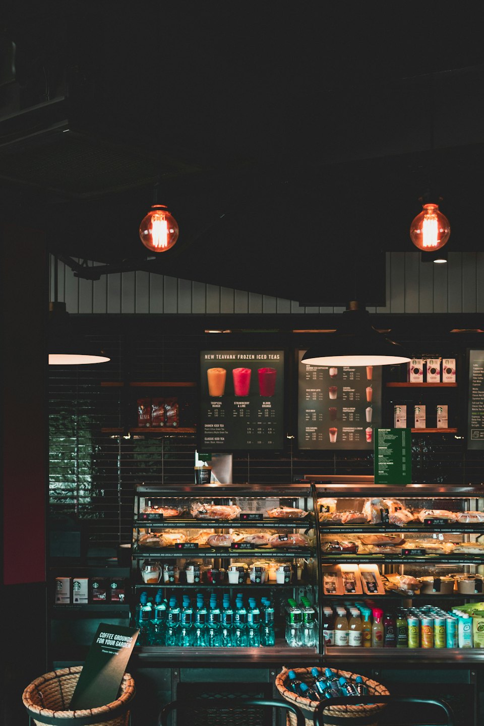 Coffee shop counter with pastry display and teal water bottles.